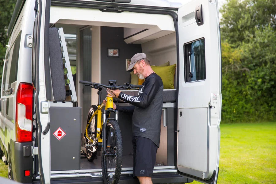A man removing his Mark2 Scrambler from the rear door of his campervan in a field