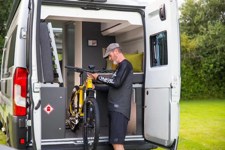 A man removing his Mark2 Scrambler from the rear door of his campervan in a field