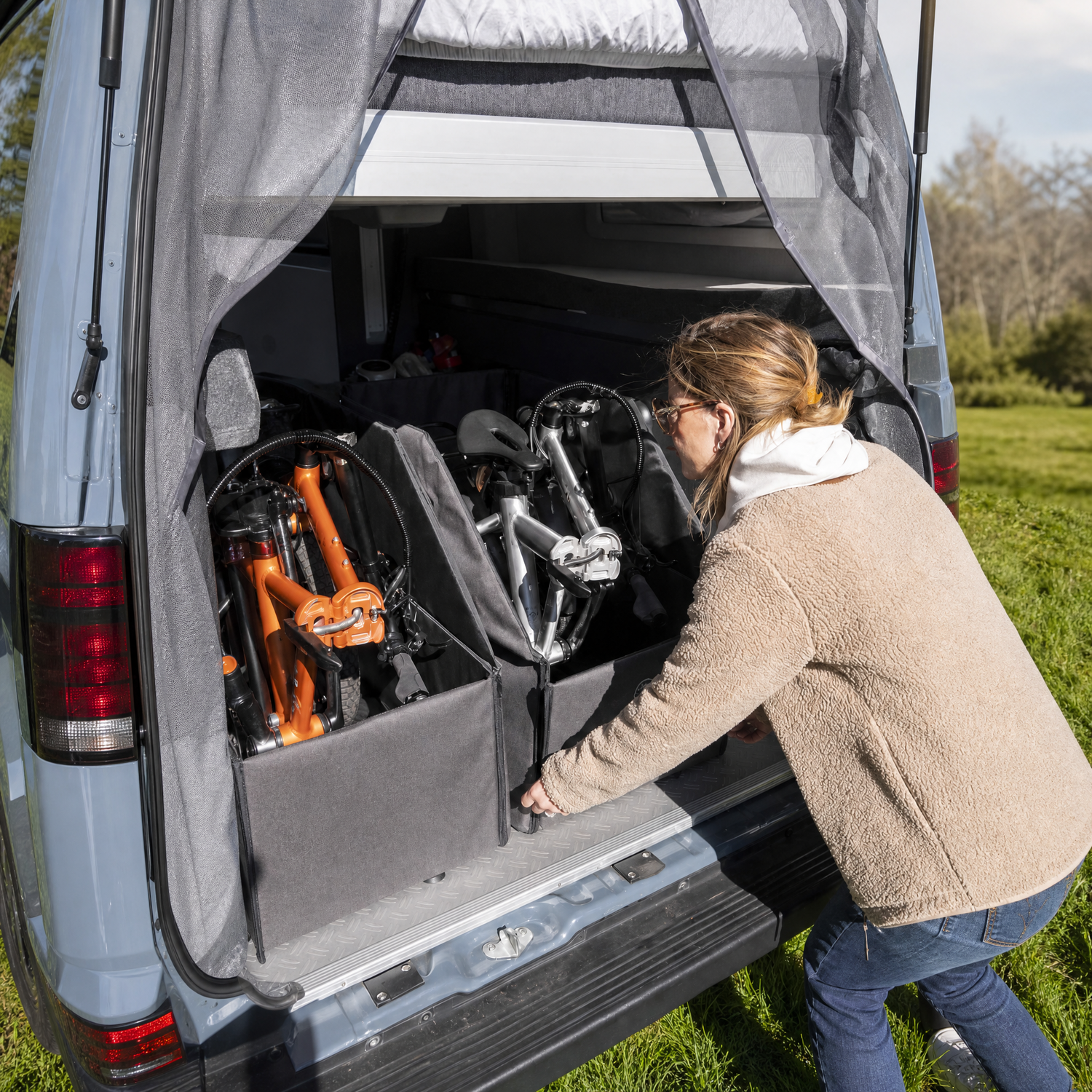 Folding electric bikebeing fitted into camper by woman in field
