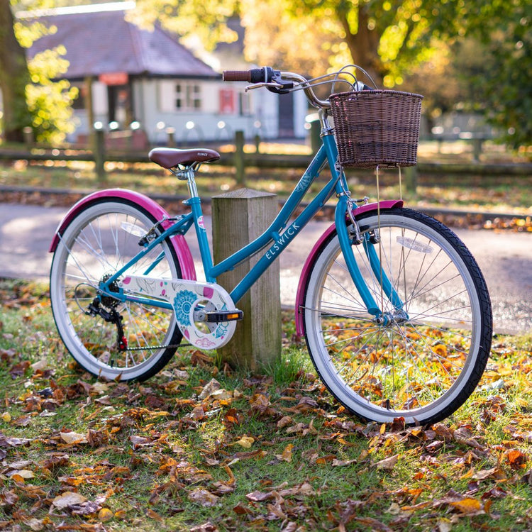 Blue & Pink Elswick traditional Heritage Juniors bike with basket leaning against a wooden post