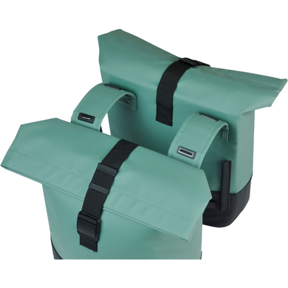 Two silvergreen/black bike panniers with black straps and green connector straps on a white background