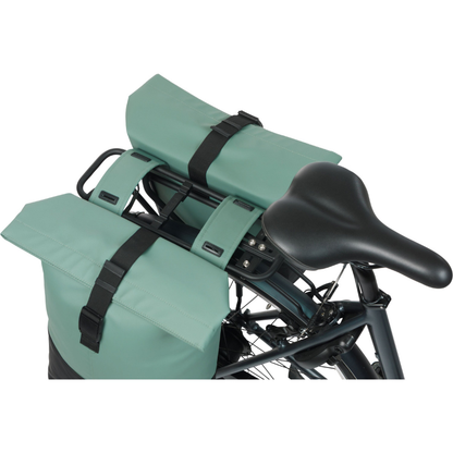 Green bicycle saddle bags with black straps on a white background on a bike