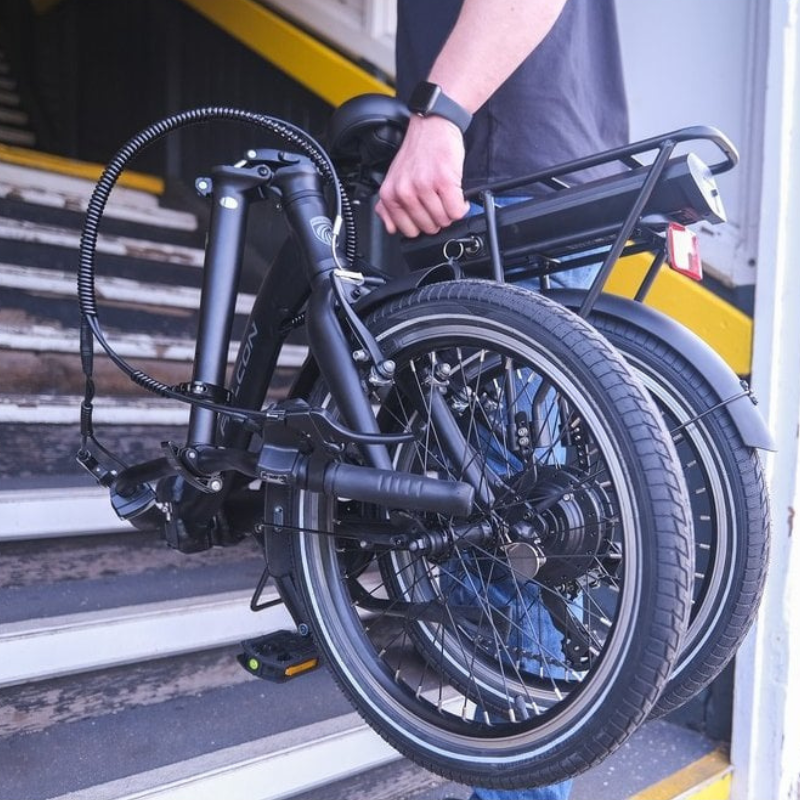 Person holding folded Falcon Breeze electric bike on a staircase