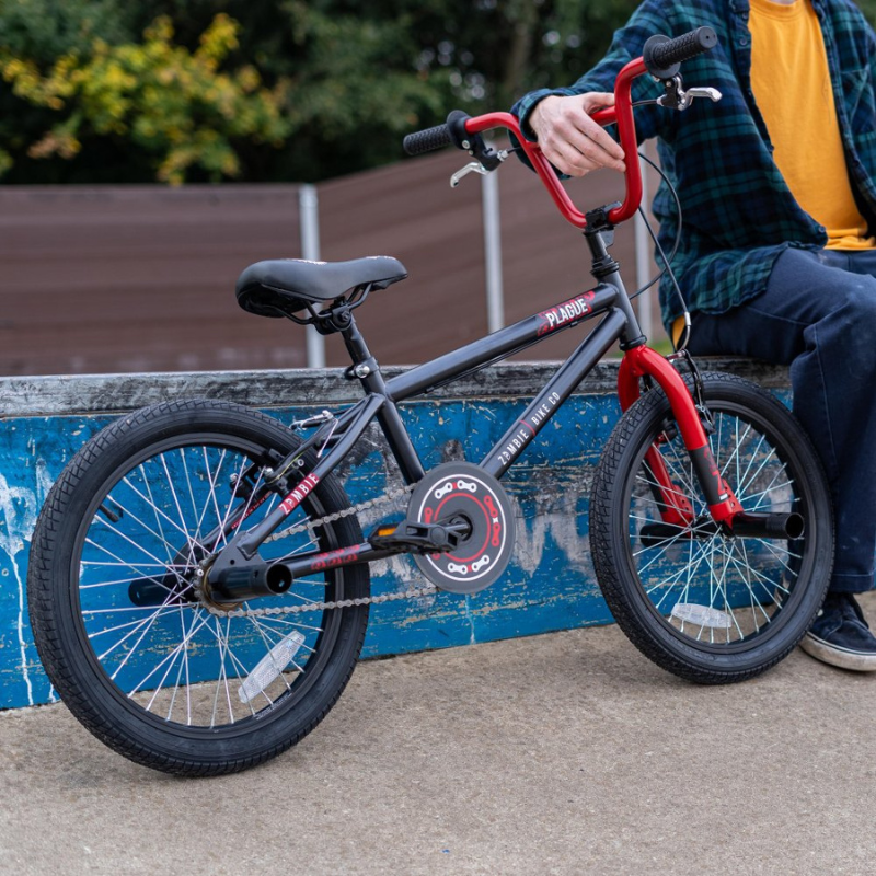 Child's bicycle with red handlebars and black frame, leaning against a blue wall.