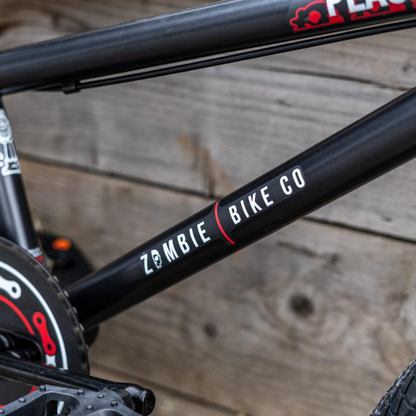 Close-up of a bicycle frame with 'Zombie Bike Co' branding against a wooden background
