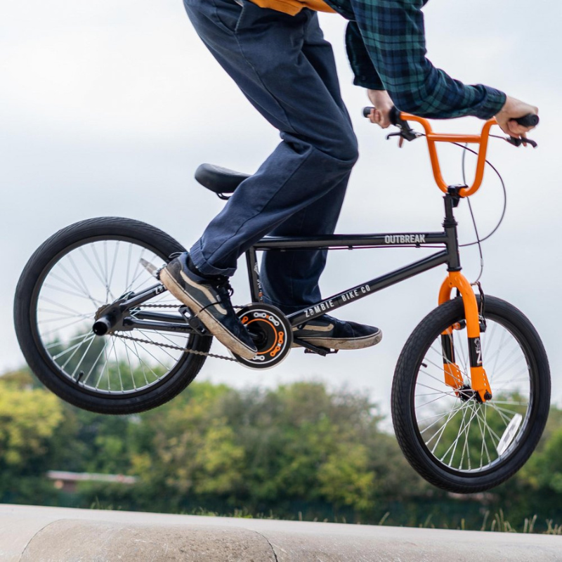Person performing a bike trick on an Outbreak BMX with a blurred green background